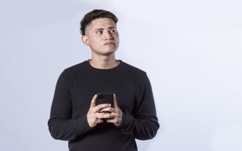 Thoughtful man holding cell phone isolated. handsome guy with pensive face holding phone on