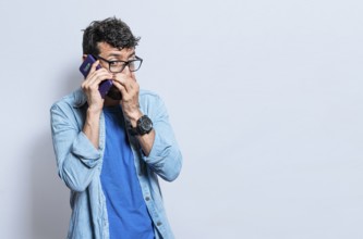 Person secretly talking on the phone. Young man secretly talking on the phone isolated, A guy