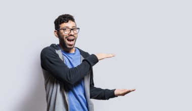 Smiling person showing an object with his palms, surprised man showing something with his palms on