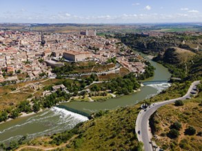 Picturesque view of a city with historic buildings stretching along a river and surrounded by hills