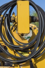 Coiled black rubber hose on yellow heavy machinery in junkyard, Quebec, Canada, North America