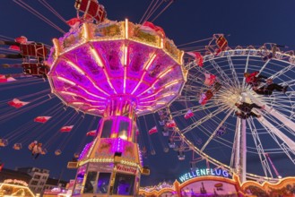 Illuminated carousel and Ferris wheel at night in a lively amusement park, funfair, wave flight,