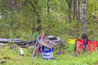 Environmental destruction with abandoned oil barrels and scrap metal in the forest