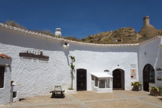 White courtyard with historic buildings and rustic ambience under a blue sky and mountains, museum,