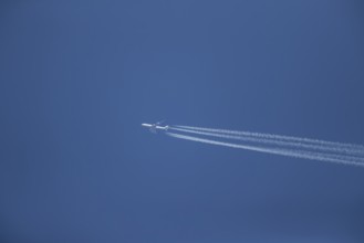 Boeing 747 aircraft of Lufthansa airlines flying across a blue sky leaving a contrail or vapor