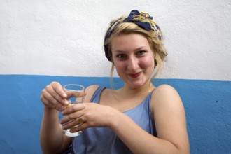 Model released portrait of teenage girl sitting holding a drink puling a silly face, UK