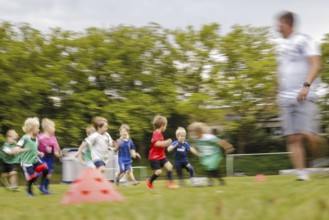 Volunteer coach trains children on the football pitch, Bonn, 19.06.2024