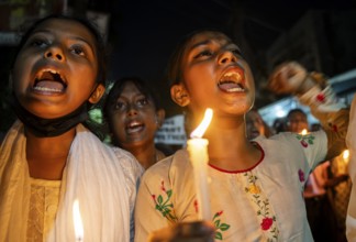 Students holds candle and shout slogans as they participate in a protest against the rape and