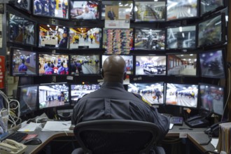 A man sits in a control room with many monitors and monitors various areas in a shopping centre, AI