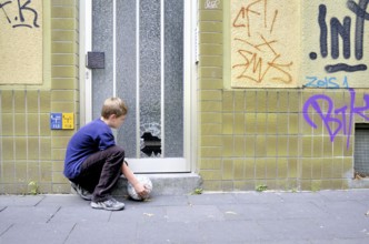 Ten-year-old boy looking at the smashed glass pane on a front door, Germany, Europe