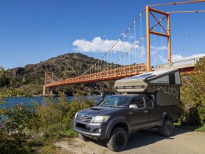 4x4 camper below famous orange suspension bridge Puente General Carrera, at lake Lago General