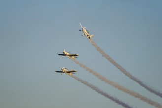 Three stunt aerobatic planes performing stunts in blue sky with smoke trail. Concept of teamwork,