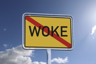 Woke symbol image: The crossed-out term WOKE on a town exit sign (Composing)