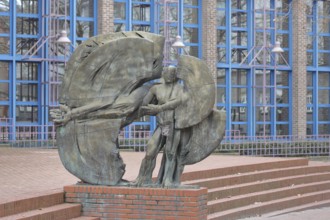 Sculpture Man in a circle by Eberhard Linke 1988, male figure with long outstretched arm, bronze