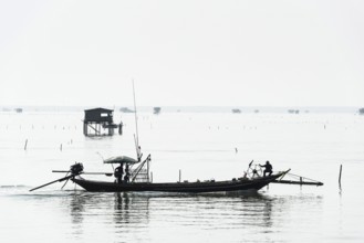 Traditional wooden huts of fishermen in the Gulf of Thailand in the morning haze, fishing boat,