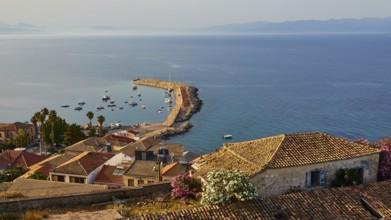 Coastal town view with harbour scenery, boats and traditional roofs surrounded by flowers, Koroni,