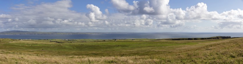 Panoramic view over wide meadows to the distant sea, Cliffs of Moher