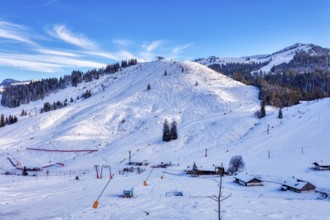 Snowy winter landscape with ski lift and huts against a clear blue sky, Sudelfeld