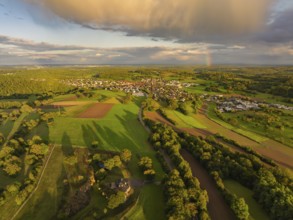 View over the village with rainbow in the distance, surrounded by green fields and gathering