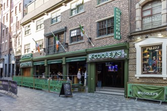 Irish pub with green awnings and flags on a cobbled street, Liverpool