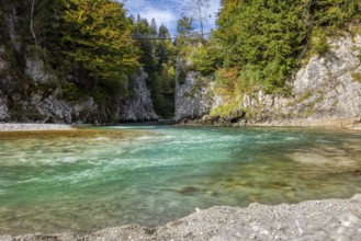 A river flows through a stony landscape with wooded slopes and a blue sky, Klobenstein