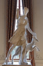 Classical statue in front of a window with decorative curtains, depicting a mythical figure, Rügen,