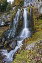 Lush waterfall flows over moss-covered rocks in autumnal surroundings, St. Beatus Caves,