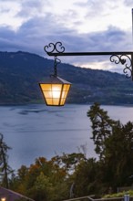 A glowing lantern with a view of a lake in a mountainous landscape, St. Beatus Caves, Switzerland,