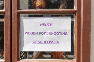 Closed shop with sign due to photo shoot in wooden frame window, Vienna