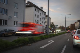 A busy street at dusk with cars and a fast passing fire engine, Stuttgart, Germany, Europe