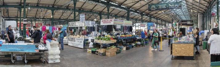 Lively marketplace under a large roof, filled with people and stalls, Belfast