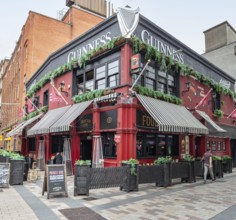 A traditionally styled pub with a red façade and green plants on the outside, Belfast