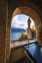 Looking through a stone arch onto a lake with mountains in the background, peaceful atmosphere,