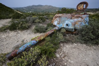 A rusty tank lies in a green landscape, surrounded by bushes, Anthony Quinn Bay, Vagies Bay,