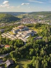 Aerial view of a town in green surroundings, many houses and a large building on a hill, blue