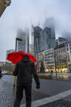 Rainy weather, freezing rain, Goetheplatz, high-rise skyline in clouds, passers-by hurrying through