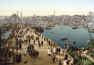 Bird's-eye view of many pedestrians and a horse-drawn carriage on the Galata Bridge spanning the