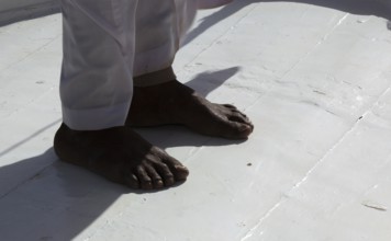 Brown feet standing on a white background, sailing ship