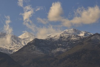 Cloudy mountain landscape with snow-capped peaks under a clear sky, Lefka Ori, White Mountains,