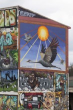 House with graffiti and mural, wild geese flying into the sun, mural by Astor Krane,