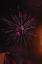 Sparkling fireworks light up the night sky above city buildings, Stuttgart Birkach, Germany, Europe