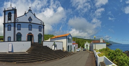 White church Igreja de São João Baptista on the village square in coastal location with clear sky