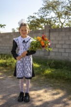 Schoolgirl with a bouquet of flowers on her first day at school, Issyk-Kul region, Kyrgyzstan, Asia