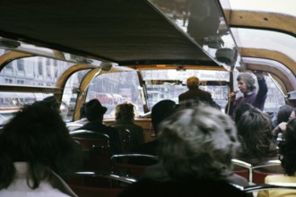 People sitting inside boat trip tour through the city centre Amsterdam, Netherlands 1973 Tour guide