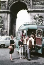 Three young people two men a woman standing by open bus door entrance older woman nearby, Arc de