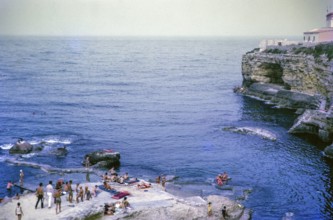 People sunbathing on rocky coastal ledge by Mediterranean Sea, Syracuse, Sicily, Italy, Europe