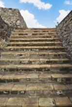 Close-up of old stairs with steps made of terracotta stone tiles and bordered by stone walls at the