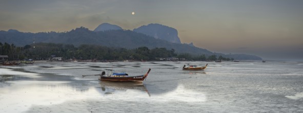 Before sunrise, longtail boats lie at low tide in the harbour at Sivalai Beach, Koh Mook Island,