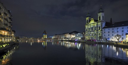 Water tower and Jesuit church on the right with light installation, on the Reuss at dusk, Old Town,