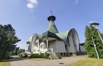 White modern church with green roof and cross against blue sky, Cathedral of the Holy Trinity,